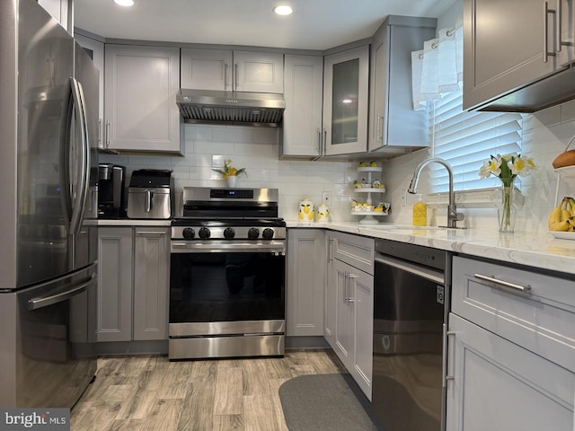 kitchen with gray cabinetry, appliances with stainless steel finishes, under cabinet range hood, and a sink
