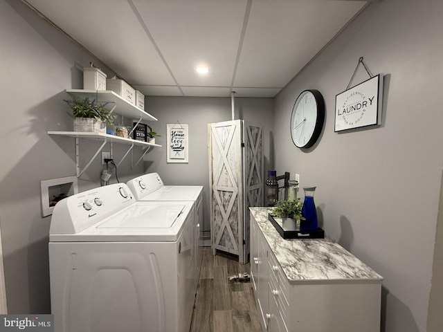 clothes washing area with separate washer and dryer, dark wood-style flooring, and cabinet space