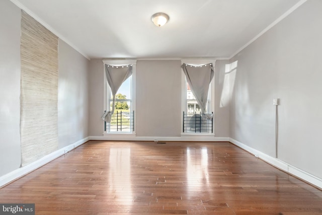 spare room with baseboards, ornamental molding, and wood finished floors