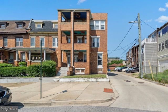 view of front of house featuring brick siding, roof with shingles, and mansard roof