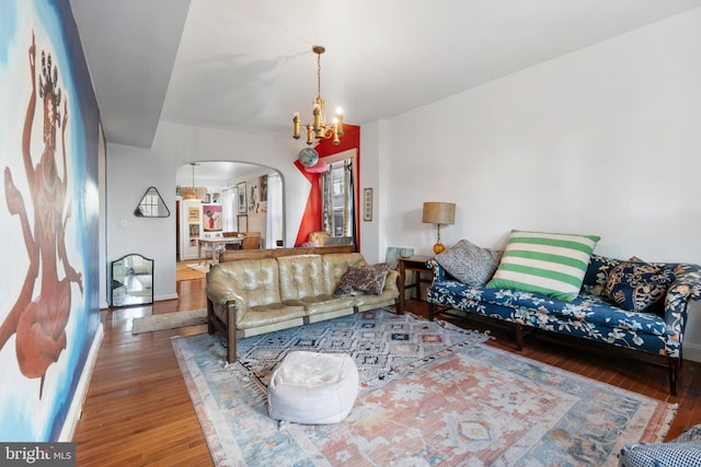 living area with an inviting chandelier, arched walkways, and hardwood / wood-style flooring