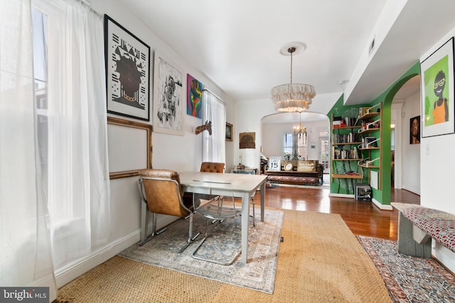 home office with baseboards, arched walkways, wood finished floors, and a notable chandelier