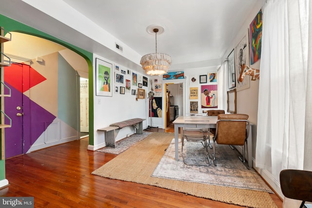 home office featuring visible vents, arched walkways, baseboards, a chandelier, and hardwood / wood-style floors