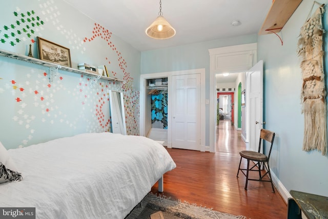 bedroom featuring baseboards, wood finished floors, and a closet