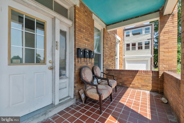 view of exterior entry with covered porch and brick siding