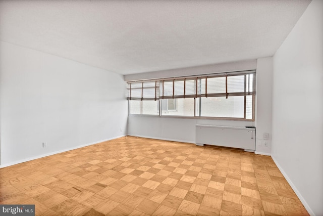 spare room featuring radiator and baseboards