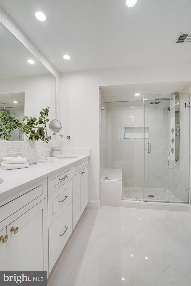 full bath with double vanity, marble look tile flooring, a stall shower, recessed lighting, and baseboards