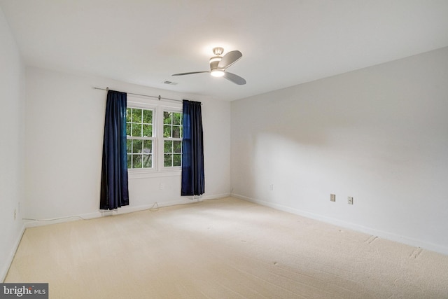 carpeted spare room with a ceiling fan and baseboards