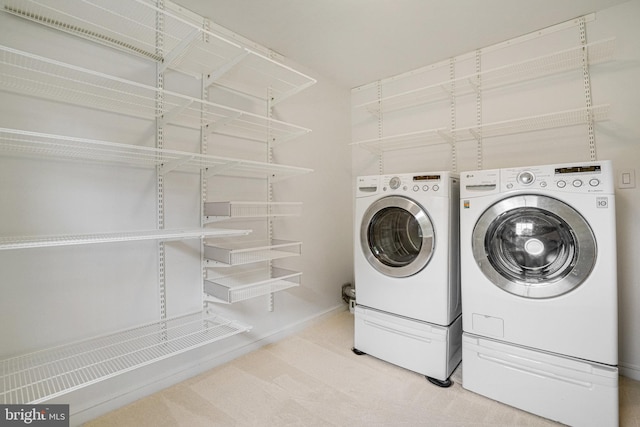 clothes washing area featuring washer and dryer, baseboards, and carpet