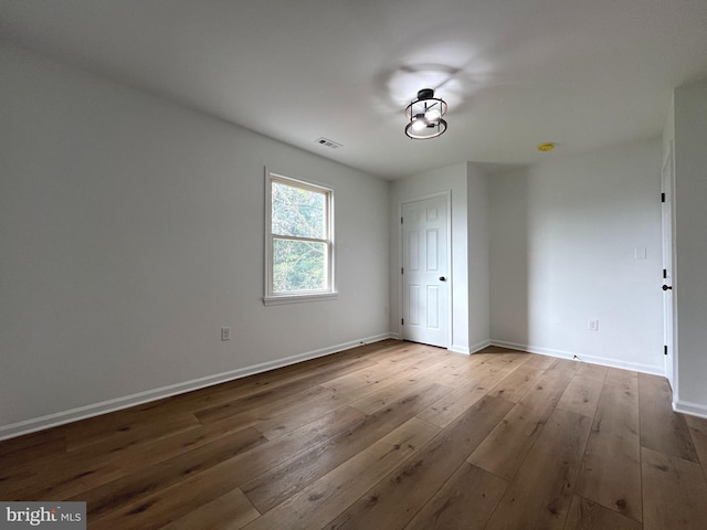 empty room with wood-type flooring, baseboards, and visible vents