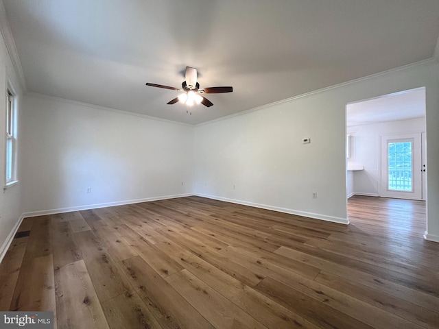 spare room featuring crown molding, baseboards, a ceiling fan, and dark wood-type flooring