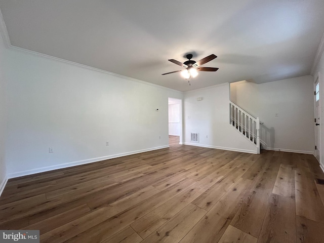 unfurnished living room with stairs, a ceiling fan, baseboards, wood finished floors, and visible vents