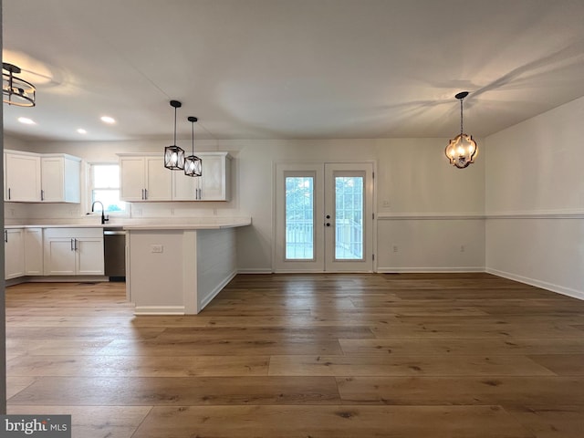 kitchen featuring baseboards, white cabinetry, hardwood / wood-style flooring, and stainless steel dishwasher