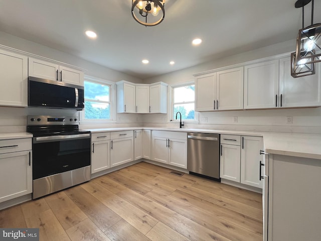 kitchen featuring white cabinets, stainless steel appliances, a wealth of natural light, and light wood-style floors
