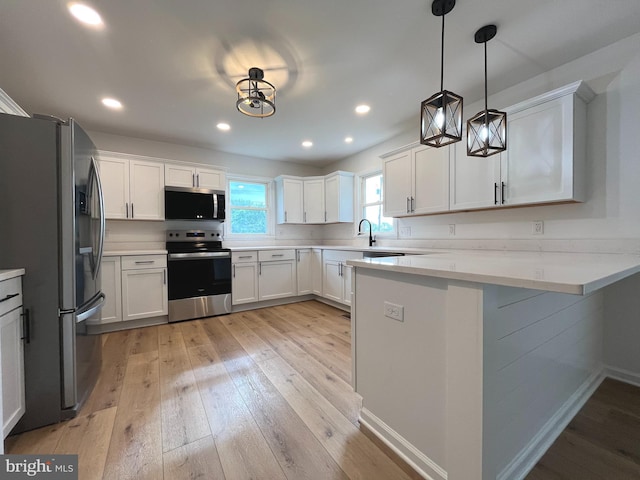 kitchen with light wood-style floors, appliances with stainless steel finishes, white cabinets, and a peninsula