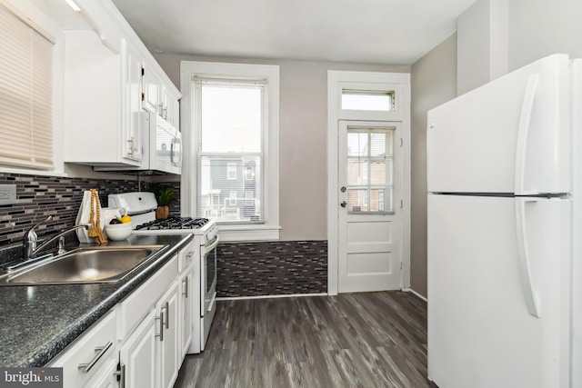 kitchen featuring dark countertops, a sink, dark wood-style floors, white appliances, and white cabinetry