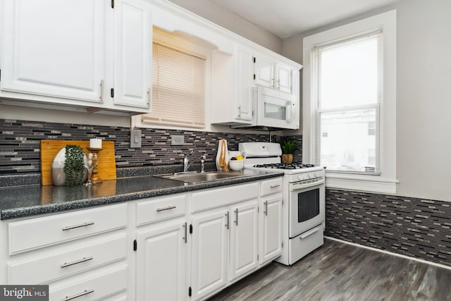 kitchen with dark wood-style flooring, dark countertops, a sink, white cabinets, and white appliances
