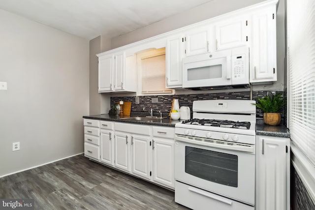 kitchen featuring white cabinets, dark countertops, a sink, white appliances, and tasteful backsplash
