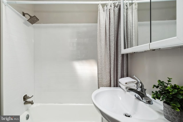 bathroom with shower / bath combo with shower curtain and a sink