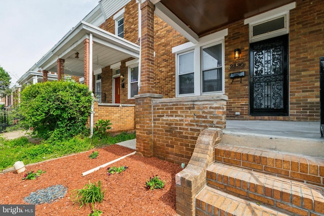 property entrance with covered porch and brick siding