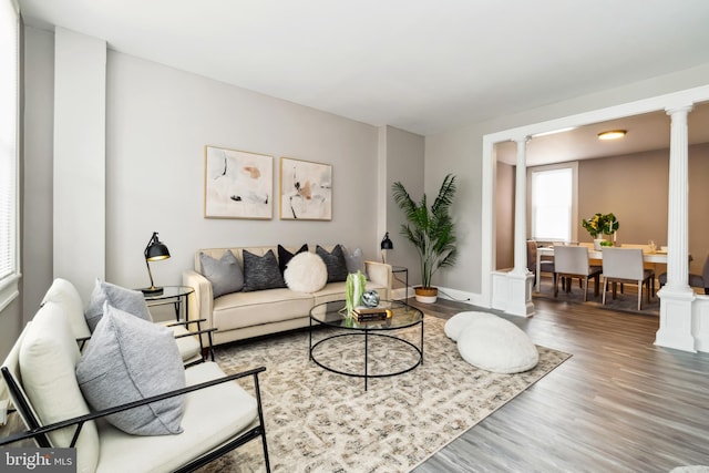 living room with baseboards, decorative columns, and wood finished floors