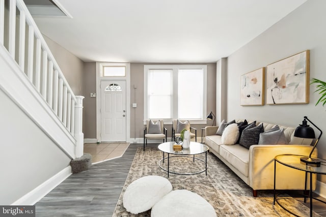 living area with baseboards, stairs, and wood finished floors