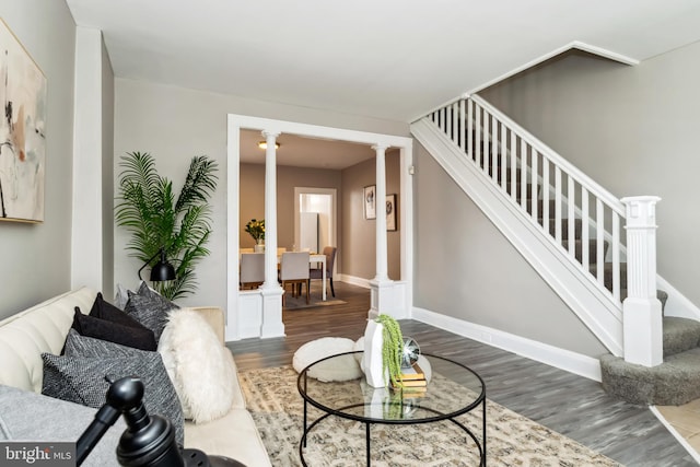 living room with stairs, decorative columns, and wood finished floors