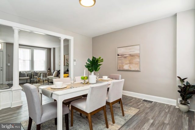 dining space featuring visible vents, decorative columns, and dark wood-style flooring