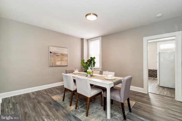 dining space featuring dark wood-style flooring and baseboards