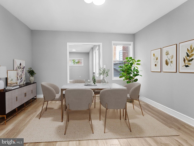 dining area featuring baseboards, plenty of natural light, and wood finished floors
