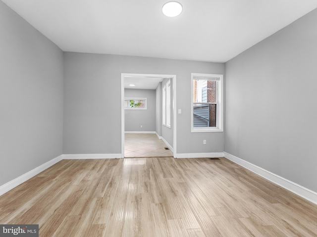 spare room featuring baseboards, light wood finished floors, and visible vents