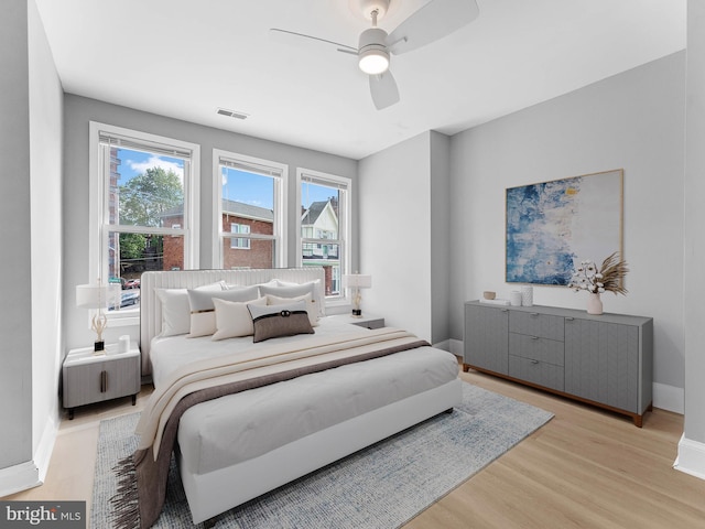 bedroom with visible vents, a ceiling fan, light wood-style floors, and baseboards