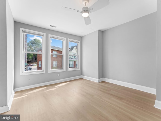 unfurnished room featuring visible vents, a ceiling fan, light wood finished floors, and baseboards