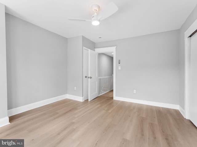 unfurnished bedroom with light wood-style floors, a ceiling fan, and baseboards