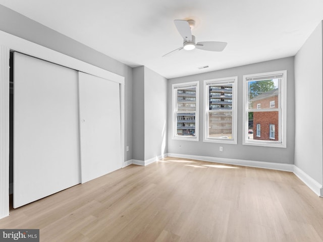 unfurnished bedroom featuring a closet, visible vents, baseboards, ceiling fan, and light wood finished floors