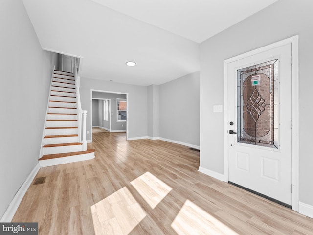 entryway with baseboards, stairs, and light wood-type flooring