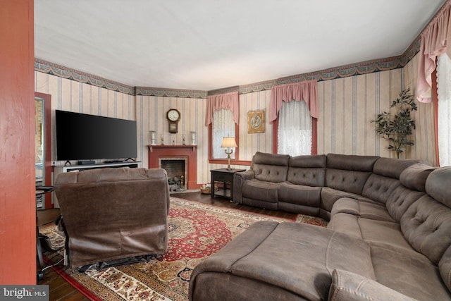 living room with a fireplace with flush hearth, wallpapered walls, and wood finished floors