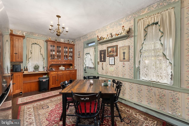 dining space featuring an inviting chandelier, a baseboard radiator, and wallpapered walls