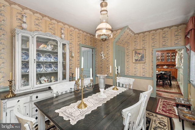 dining room with wallpapered walls and a notable chandelier