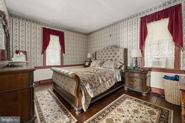bedroom with wood-type flooring, wallpapered walls, multiple windows, and baseboard heating