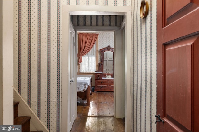 hallway with wood-type flooring and wallpapered walls