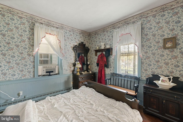 bedroom featuring a wainscoted wall, a baseboard heating unit, wallpapered walls, and wood finished floors