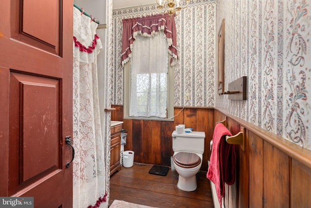bathroom featuring a wainscoted wall, toilet, hardwood / wood-style floors, and wallpapered walls