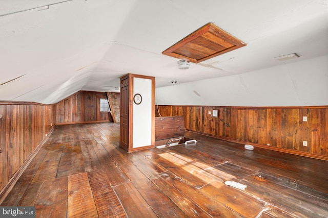 bonus room featuring wooden walls, wainscoting, wood-type flooring, baseboards, and lofted ceiling