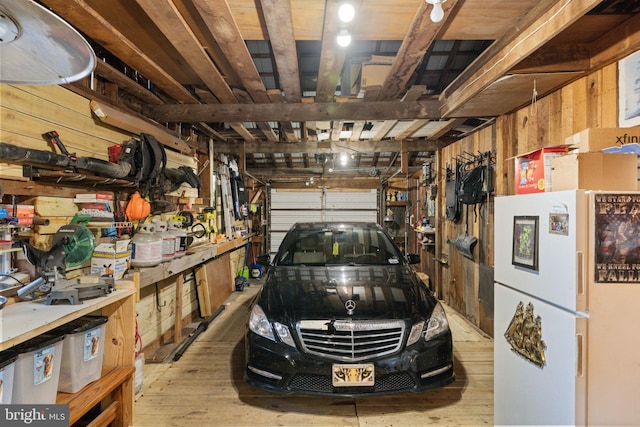 garage with freestanding refrigerator, wooden walls, and a workshop area