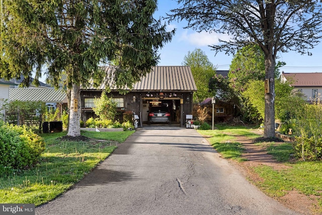 view of front of property featuring an attached garage, driveway, and metal roof