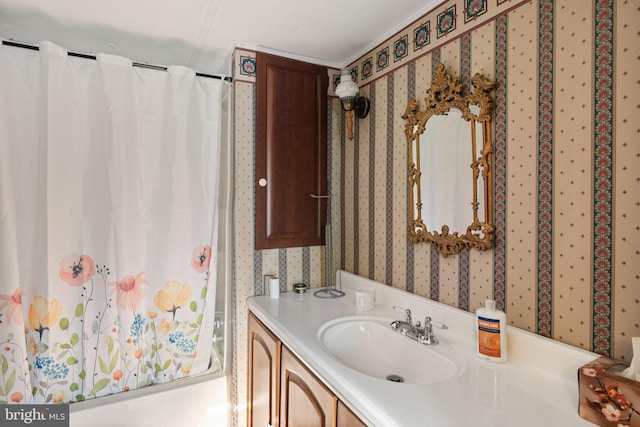 bathroom featuring vanity, shower / tub combo, and wallpapered walls