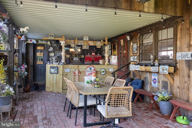 dining space with wooden walls and brick floor