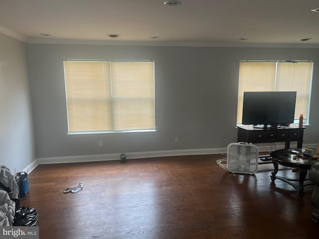 unfurnished living room featuring ornamental molding, healthy amount of natural light, wood finished floors, and baseboards