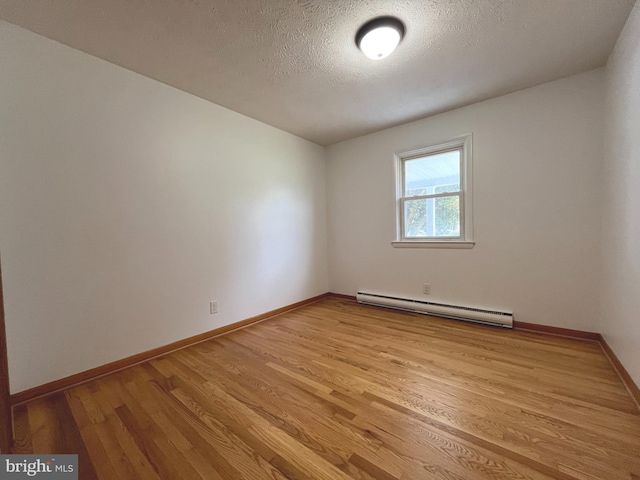 empty room with baseboards, a baseboard radiator, a textured ceiling, and light wood-style flooring